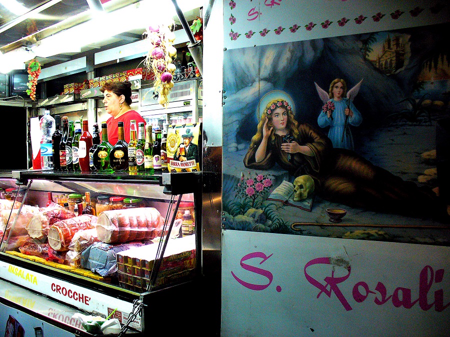 A night food kiosk in Palermo (Sicily, Italy), displaying a poster of the city's patron saint, Santa Rosalia or "Santuzza". Palermo celebrates its patron saint in July.